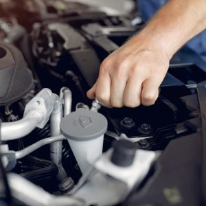 Wrker in a car salon. Expert checks the car. Man in a blue uniform.